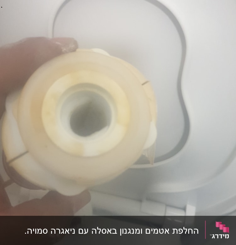 יד מחזיקה חלק פלסטיק מול אסלה לבנה